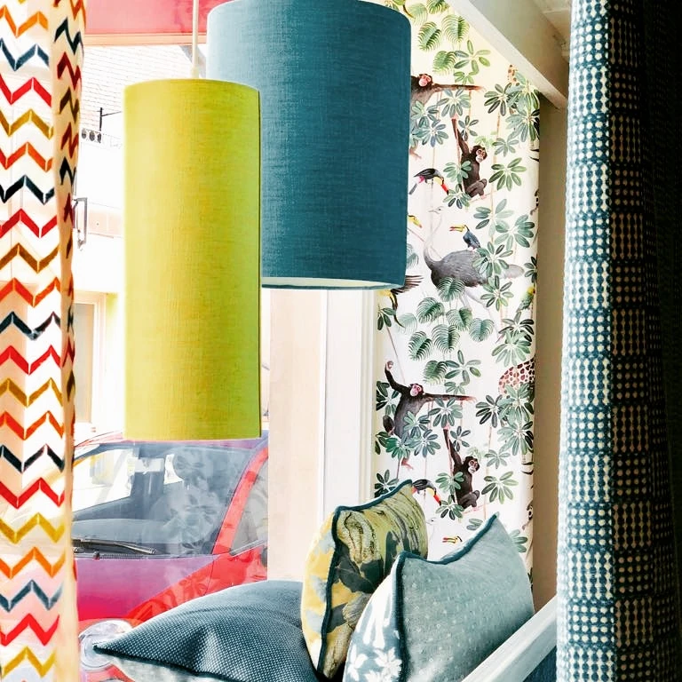 Bunte Lampenschirme über Kissen und gemusterten Stoffen in einem Schaufenster