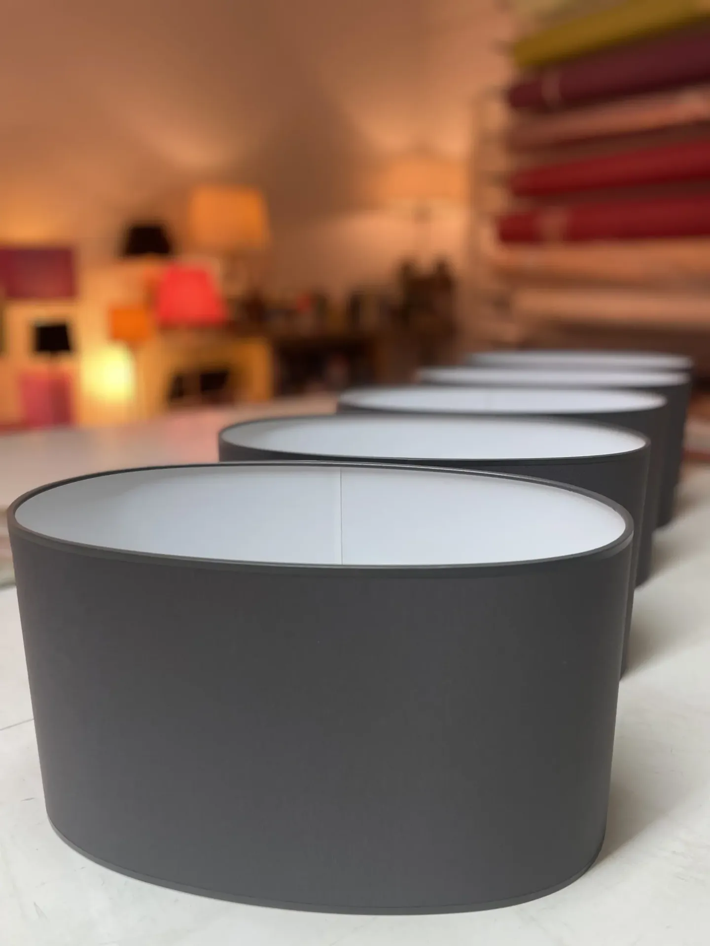 Reihe grauer ovaler Lampenschirme auf einem Ausstellungstisch