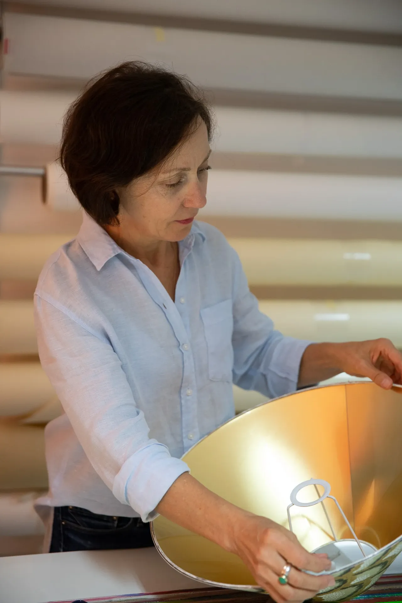 Marina Hummel prüft einen goldfarbenen Lampenschirm in ihrer Werkstatt