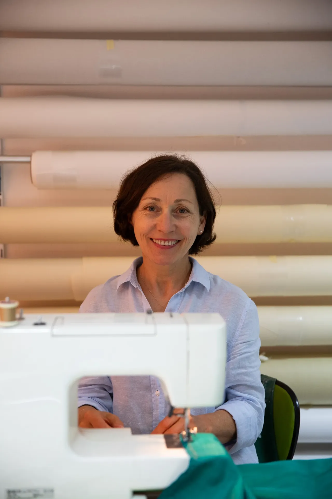 Marina Hummel lächelnd an der Nähmaschine, sie näht Stoff für einen Lampenschirm