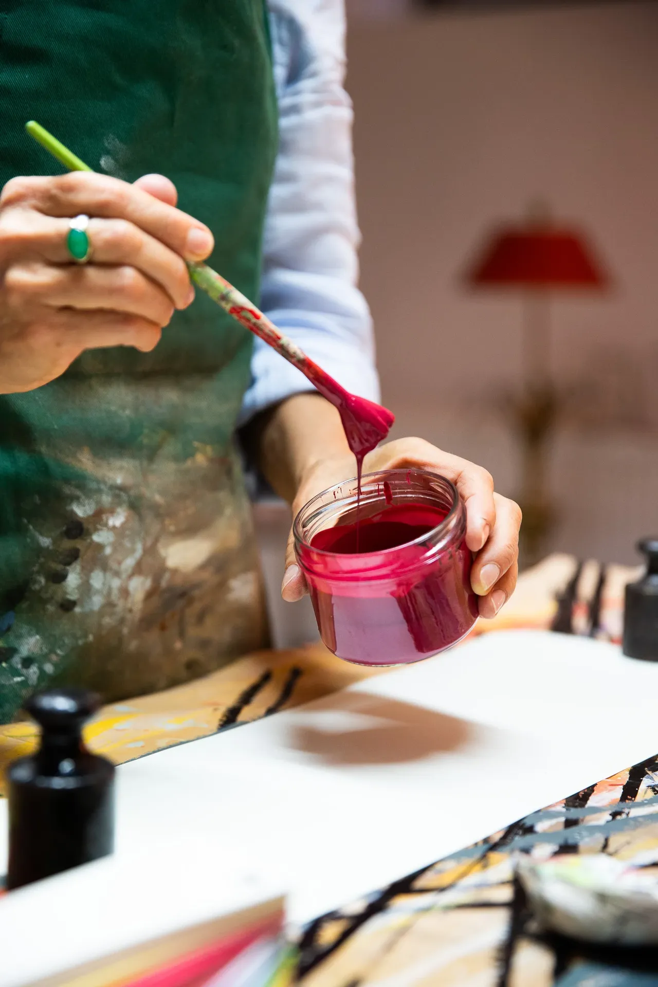 Person trägt mit Pinsel pinke Farbe aus einem Glas auf eine weiße Fläche auf