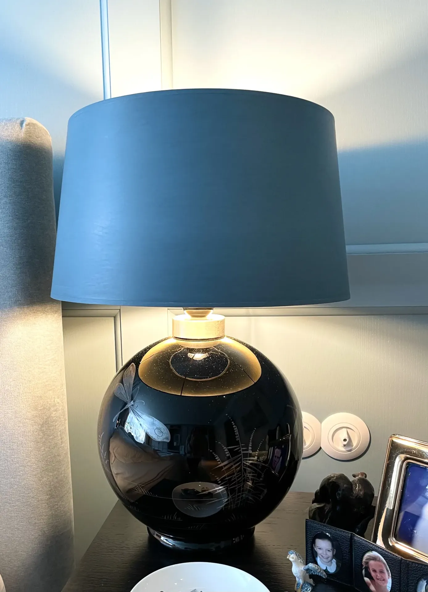 Tischlampe mit dunkelblauem Stoffschirm und schwarzer Glaskugel-Basis auf einem Nachttisch