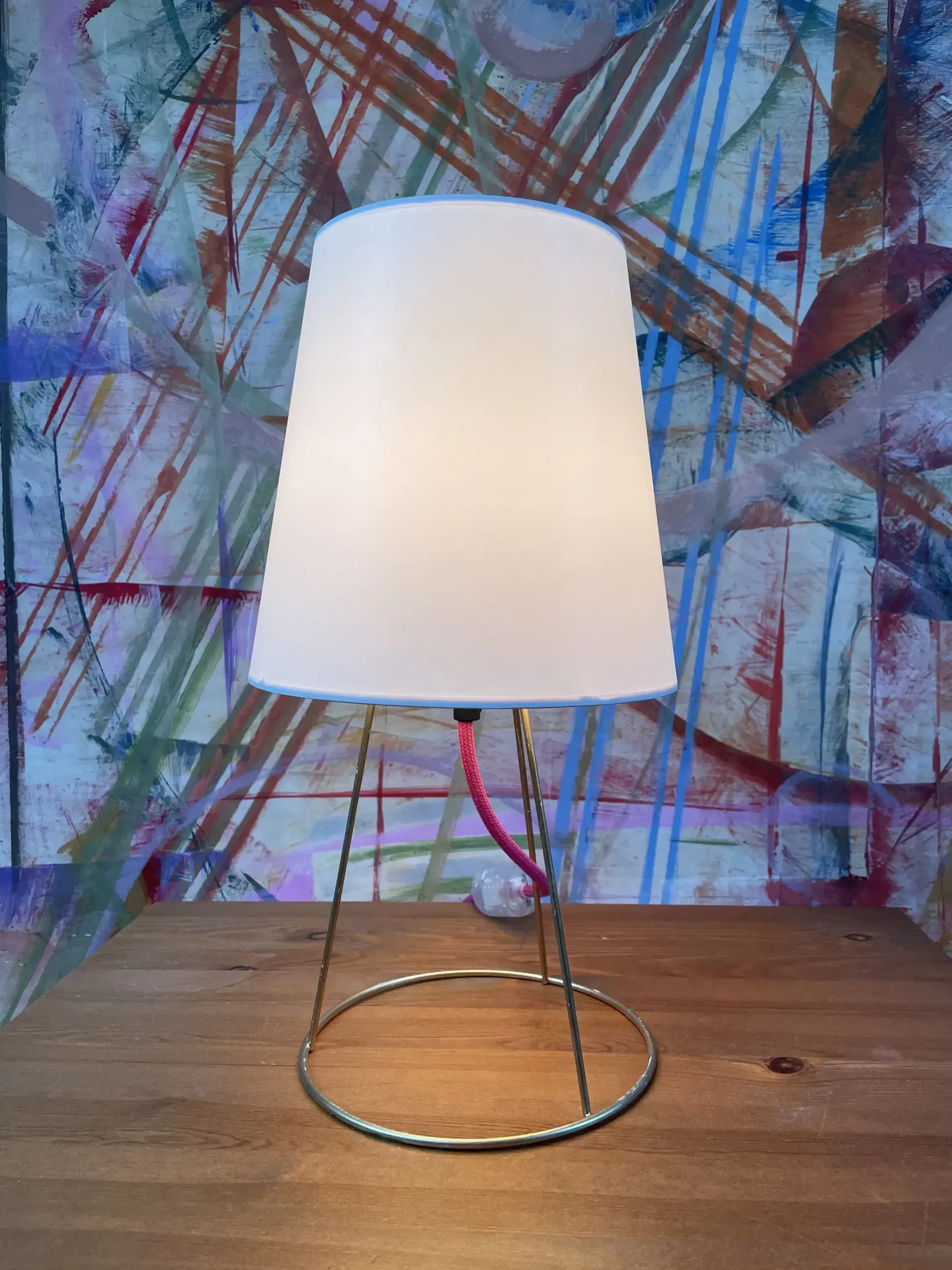 Tischlampe mit weißem Schirm und schlankem Metallgestell auf Holztisch