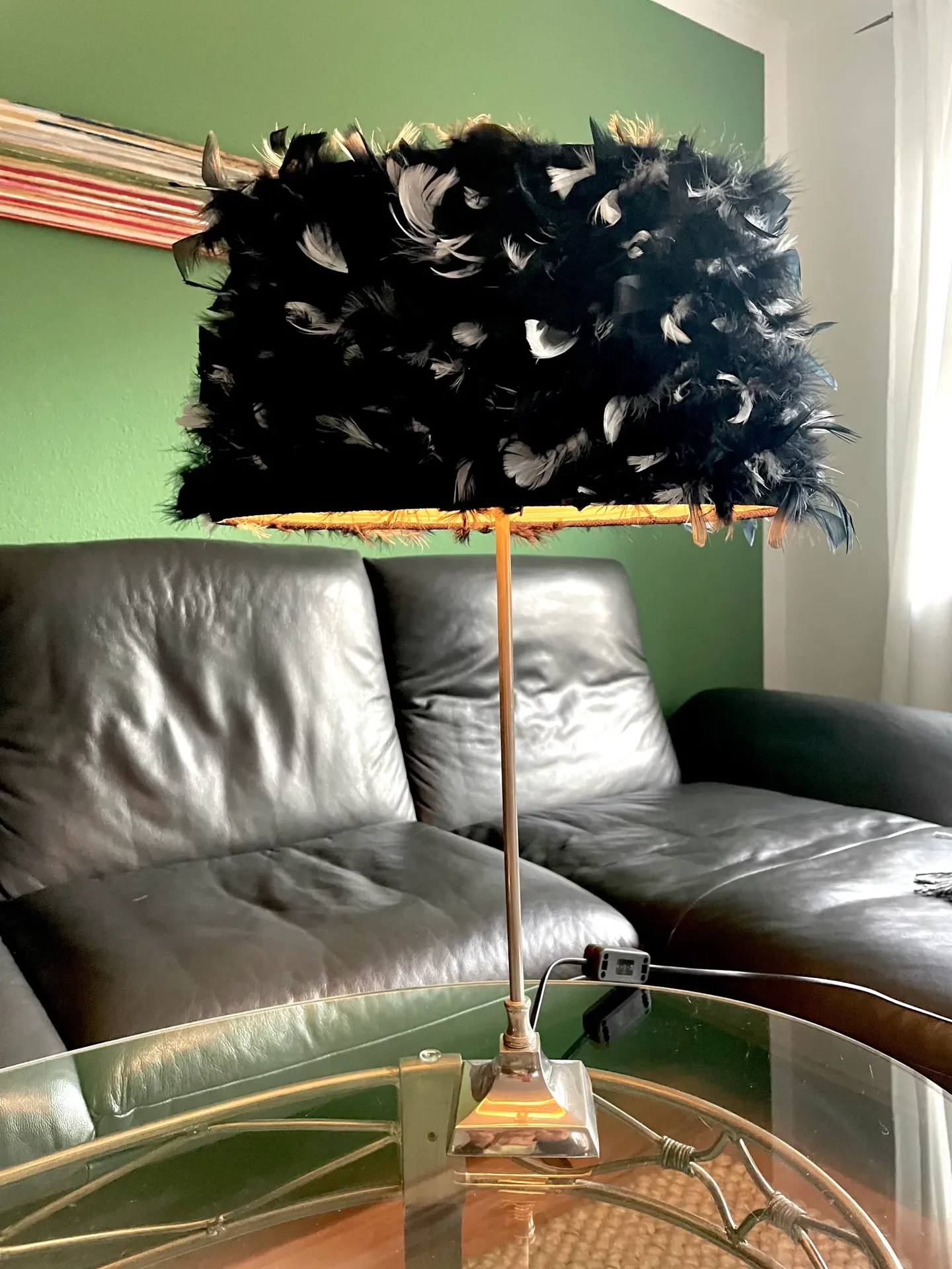 Tischlampe mit schwarzem Federschirm auf einem Glastisch im Wohnzimmer