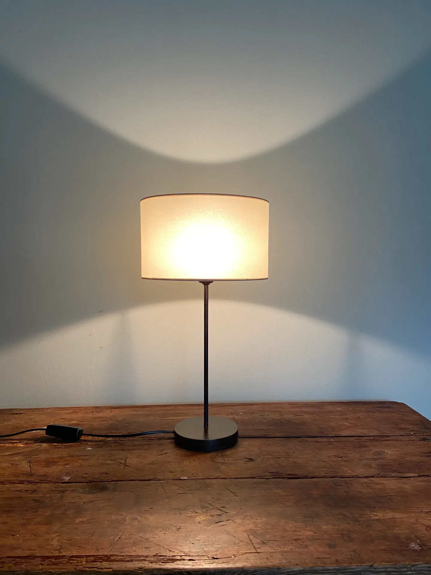 Tischlampe mit rundem Lampenschirm auf Holztisch, spendet warmes Licht