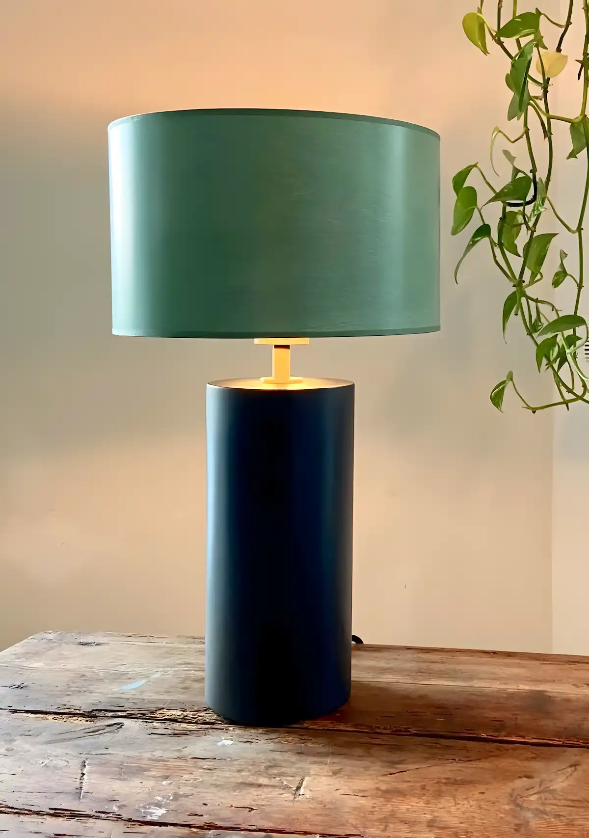 Dunkeltürkise Tischlampe mit rundem Schirm auf rustikalem Holztisch