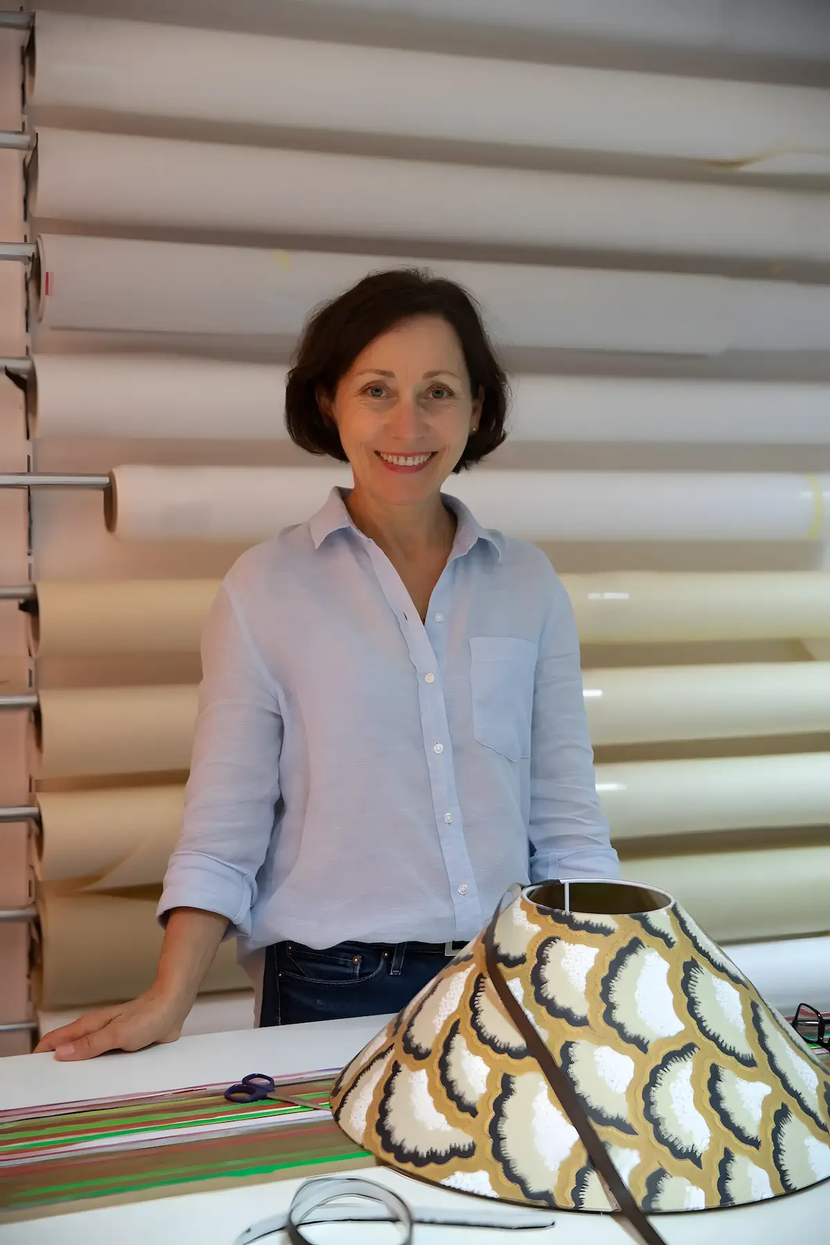 Marina Hummel lächelnd in ihrer Werkstatt, vor ihr ein Lampenschirm auf dem Tisch