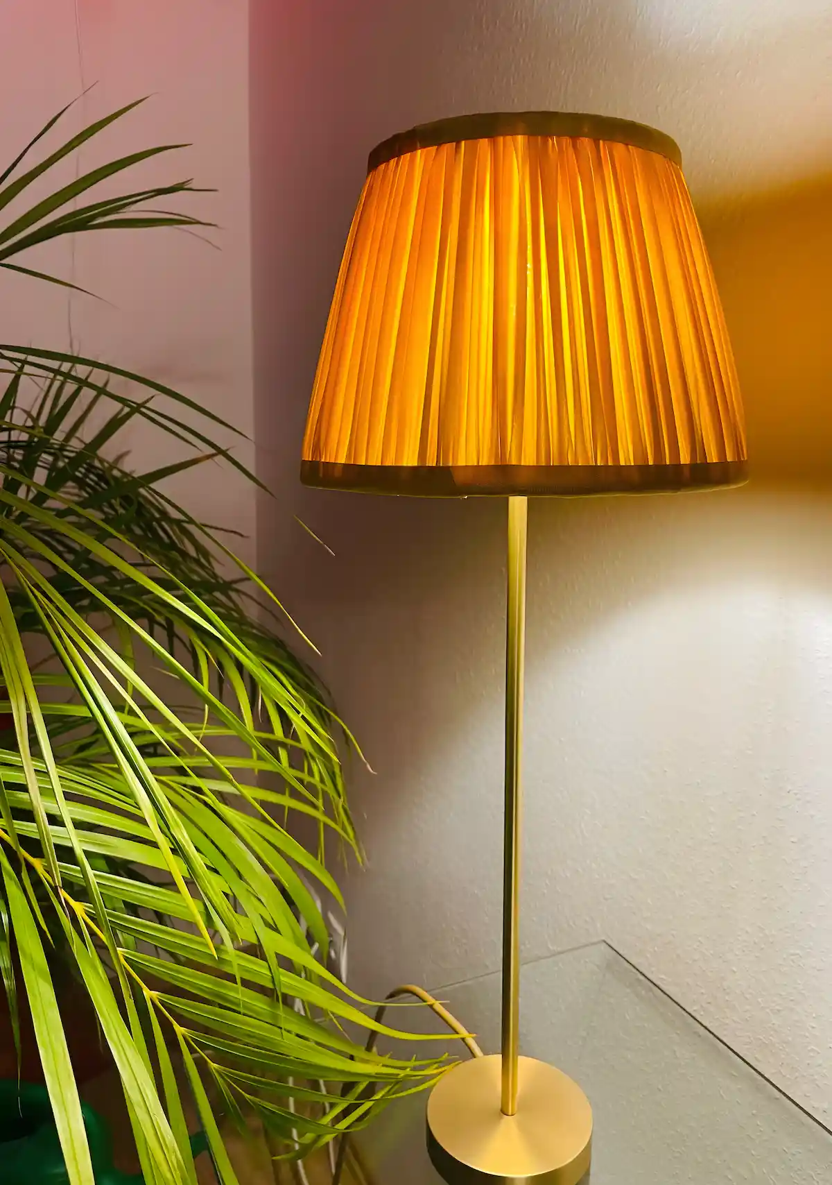 Orangene Stehlampe mit plissiertem Schirm spendet warmes Licht in einer Wohnecke