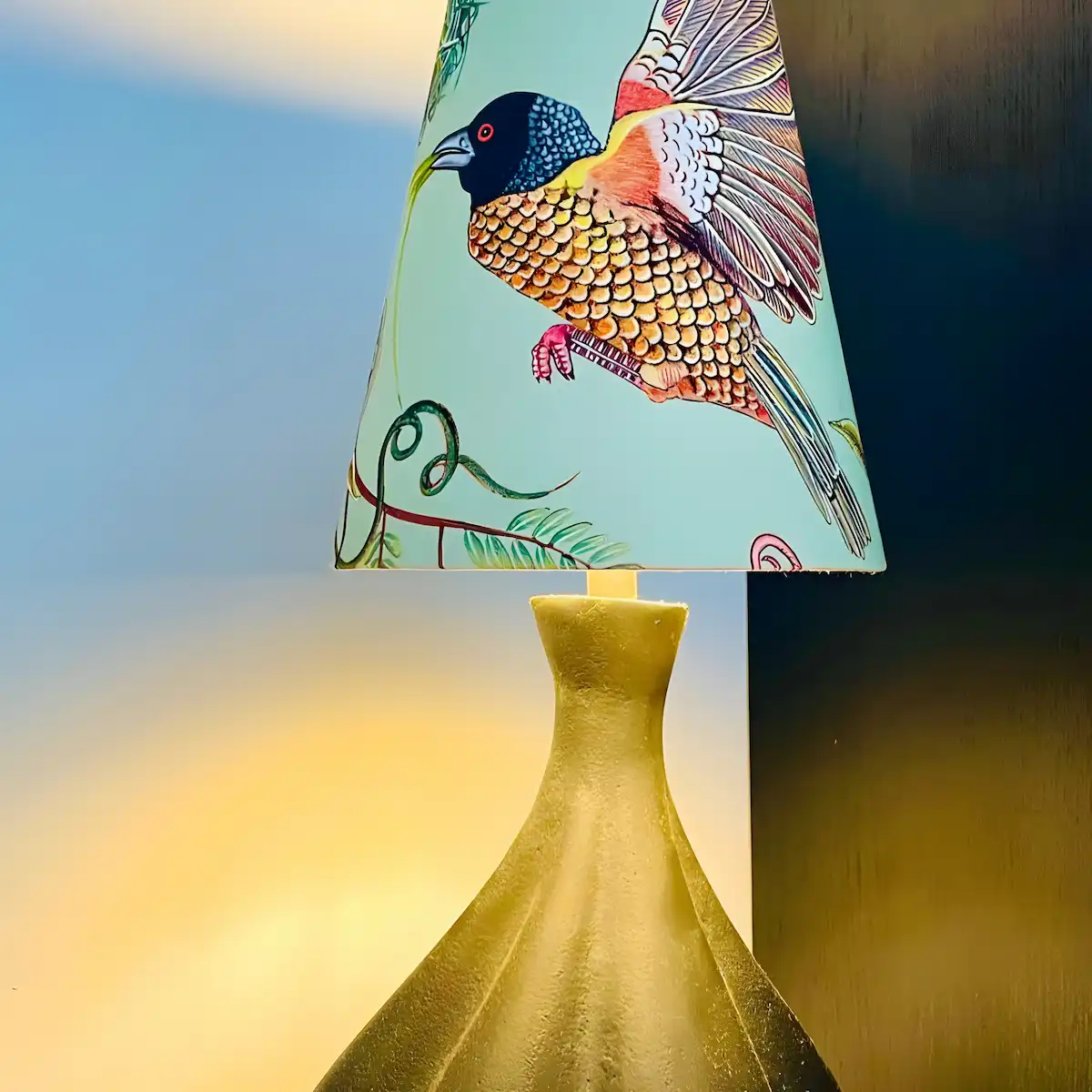 Ovaler Lampenschirm mit buntem Vogelmotiv an einer Tischlampe